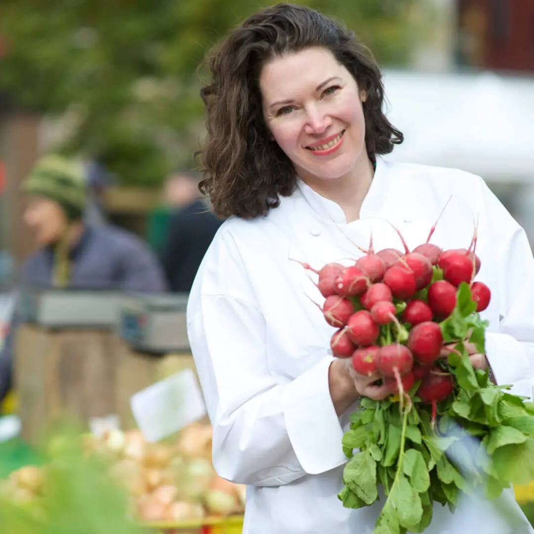 A woman holding radishes in her hands.