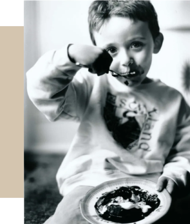 A young boy eating food from a plate.